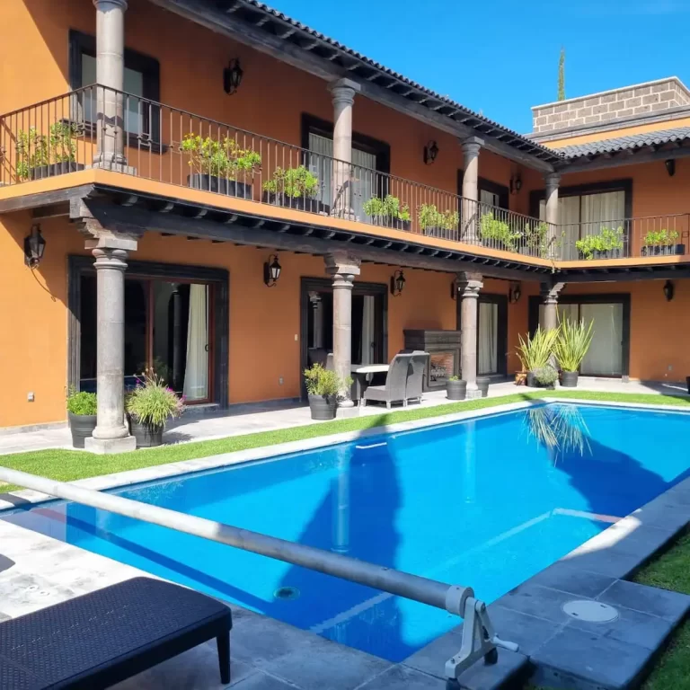 The exterior of Villa Serena, a two-story house with terracotta-colored walls, a swimming pool, and a balcony. - Villa Serena