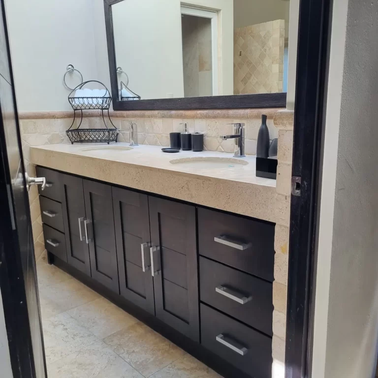 A spacious bathroom vanity at Villa Serena with a double sink, a marble countertop, and dark cabinets. - Villa Serena