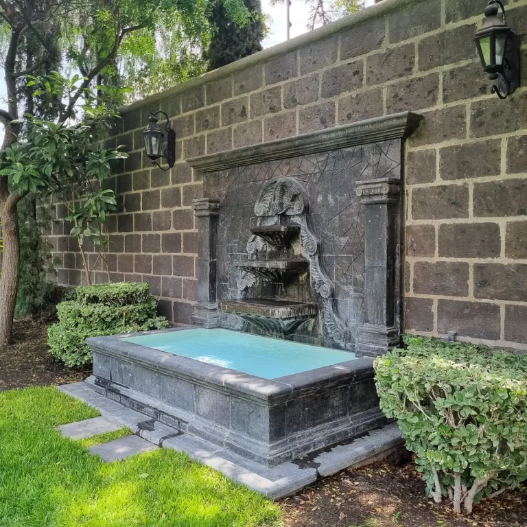 A beautiful stone fountain surrounded by greenery in the garden of Villa Serena. - Villa Serena