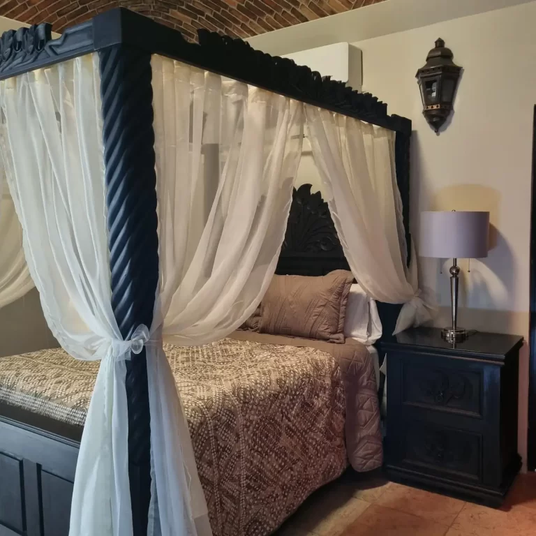 A four-poster bed with sheer white curtains in a bedroom at Villa Serena. - Villa Serena